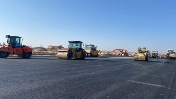 近日，在西部市政建設(shè)集團(tuán)蘭州新區(qū)城市礦產(chǎn)與表面處理產(chǎn)業(yè)園區(qū)（二期）周邊基礎(chǔ)設(shè)施項目—園區(qū)西路南延段（緯五十路至緯二十八路）項目現(xiàn)場，隨著一輛輛運料車平穩(wěn)駛?cè)耄瑪備仚C(jī)將滾燙的瀝青混合料均勻鋪開，標(biāo)志著項